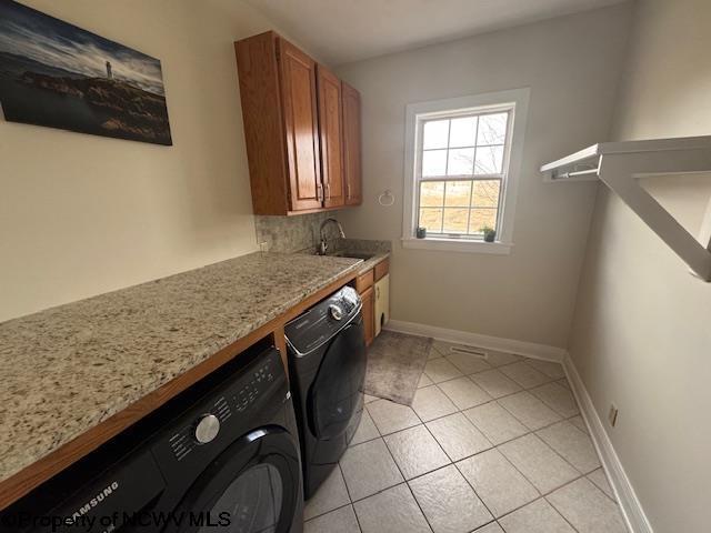 laundry room with light tile patterned flooring, a sink, baseboards, washer and dryer, and cabinet space