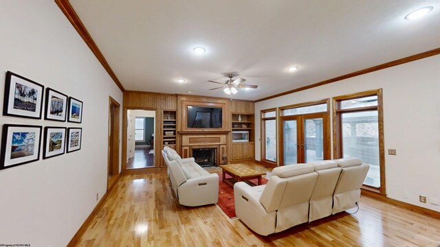 living room featuring baseboards, a fireplace with flush hearth, ornamental molding, french doors, and light wood-style floors