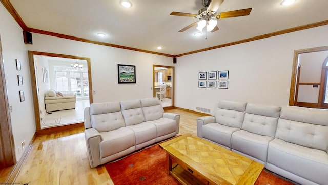 living area featuring light wood-type flooring, visible vents, and crown molding