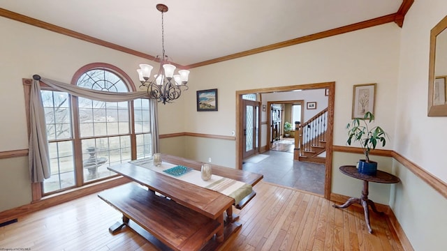 dining space featuring light wood-type flooring, a healthy amount of sunlight, a notable chandelier, and crown molding