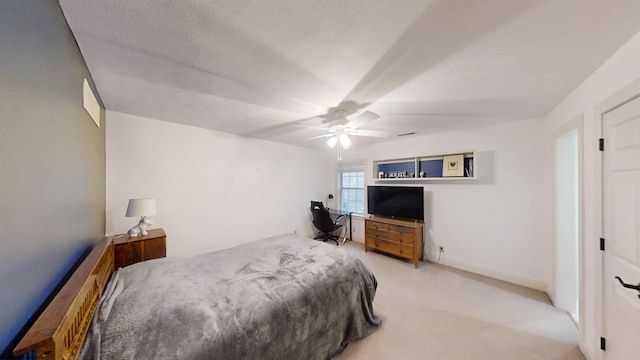 bedroom featuring a ceiling fan, light colored carpet, a textured ceiling, and baseboards