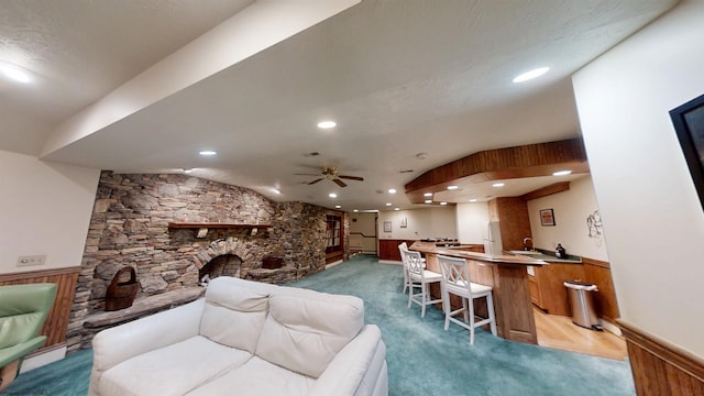 interior space featuring a wainscoted wall, recessed lighting, ceiling fan, and a stone fireplace