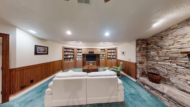 carpeted living area featuring recessed lighting, visible vents, wainscoting, wooden walls, and a textured ceiling