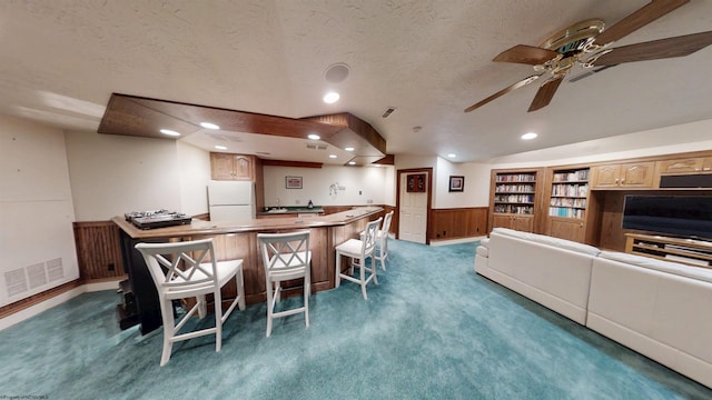 interior space featuring a textured ceiling, carpet floors, visible vents, wainscoting, and wet bar