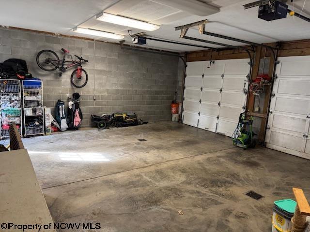 garage with a garage door opener and concrete block wall