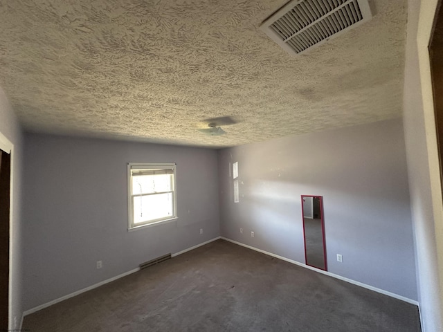 empty room with a textured ceiling, visible vents, and baseboards