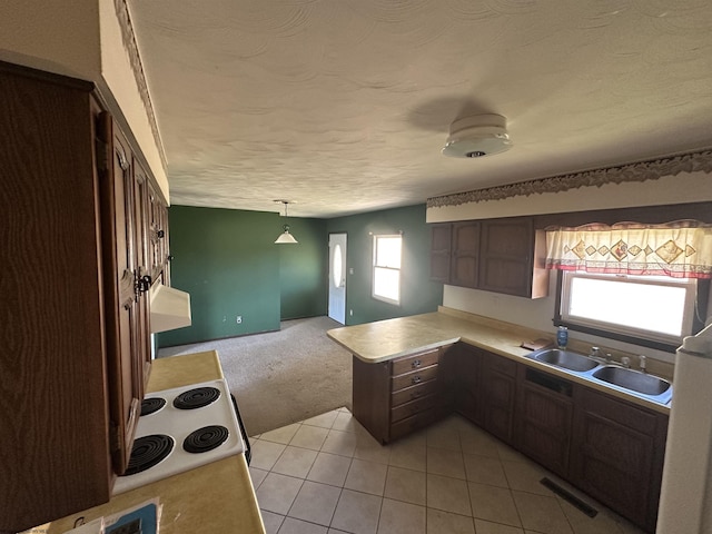 kitchen with a textured ceiling, a peninsula, visible vents, light countertops, and white range with electric stovetop