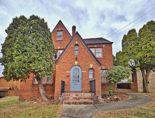 tudor home with brick siding and a chimney