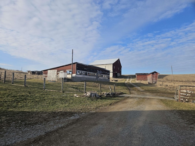 view of yard with dirt driveway, a rural view, a detached garage, and fence