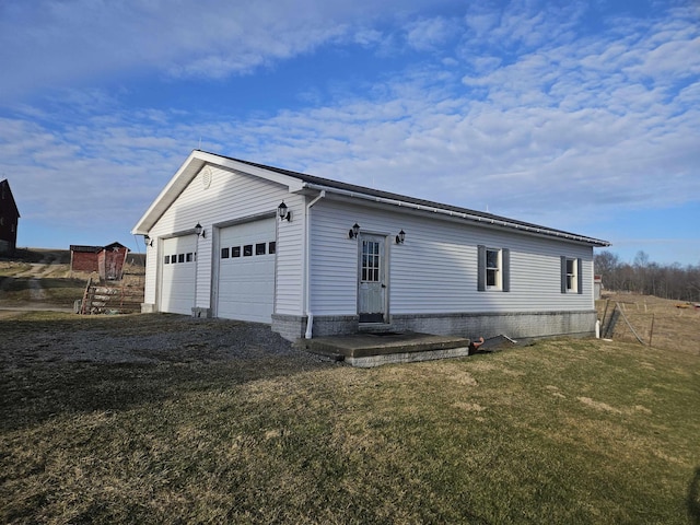 view of property exterior with an attached garage, a lawn, driveway, and an outdoor structure