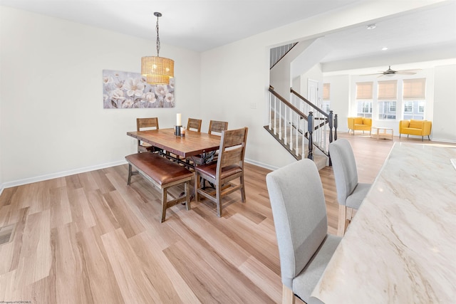 dining space with a ceiling fan, light wood-type flooring, stairway, and baseboards