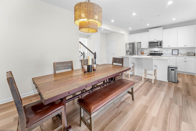 dining room featuring baseboards, stairway, light wood-style floors, a chandelier, and recessed lighting