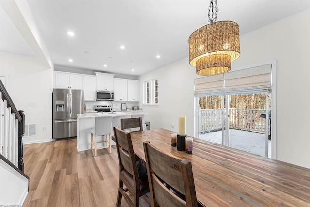 dining room featuring recessed lighting, visible vents, stairs, light wood finished floors, and an inviting chandelier