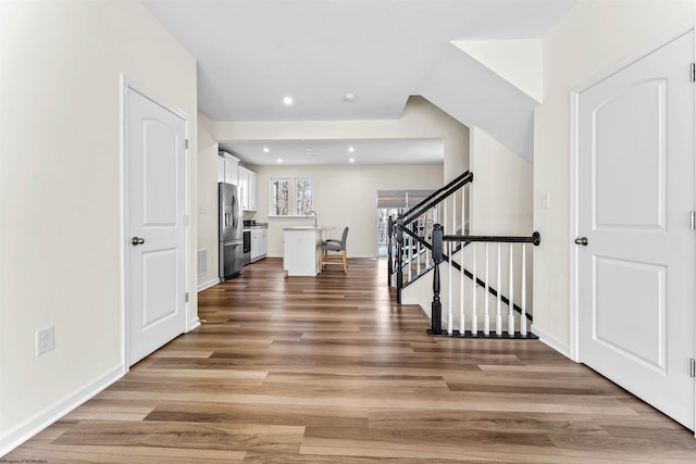 foyer featuring baseboards, visible vents, stairway, and light wood finished floors