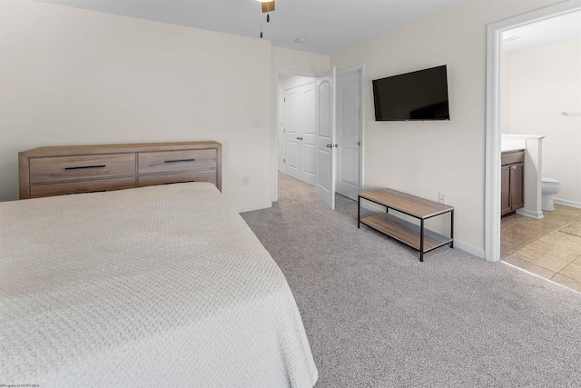 bedroom featuring light carpet, ensuite bath, and baseboards