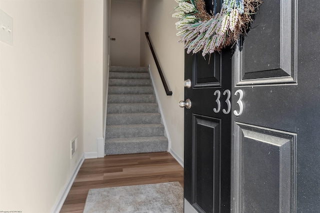 stairs with wood finished floors, visible vents, and baseboards