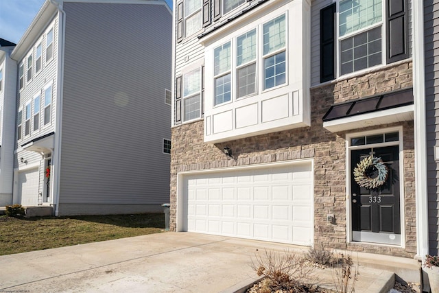 exterior space featuring concrete driveway, stone siding, and an attached garage