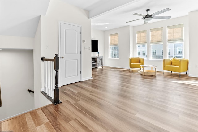 unfurnished room featuring light wood-style flooring, baseboards, a ceiling fan, and an upstairs landing