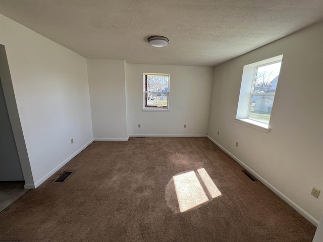 unfurnished room with carpet, visible vents, a textured ceiling, and baseboards