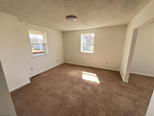 unfurnished bedroom featuring carpet floors, visible vents, a textured ceiling, and baseboards