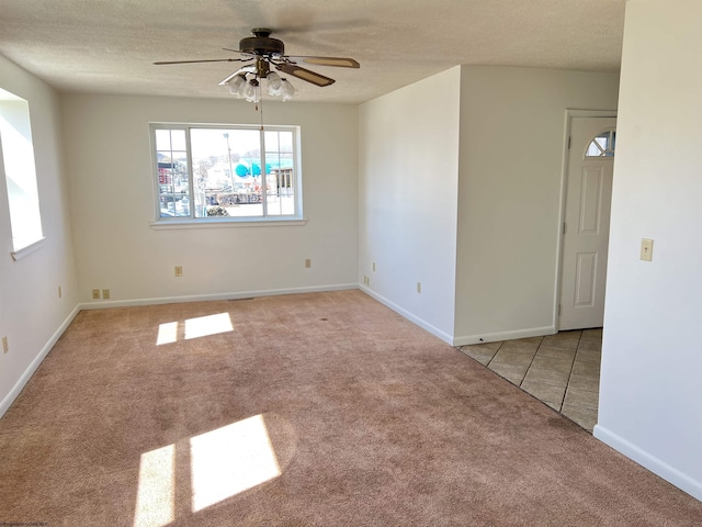 tiled spare room with ceiling fan, a textured ceiling, baseboards, and carpet flooring