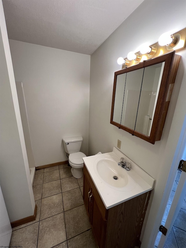 bathroom featuring a textured ceiling, toilet, vanity, baseboards, and tile patterned floors