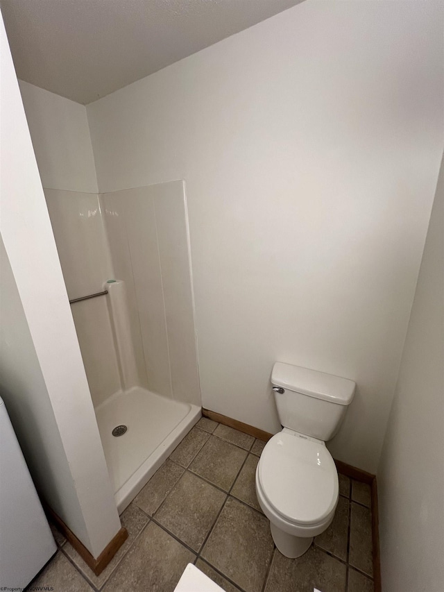 full bathroom featuring toilet, a stall shower, tile patterned flooring, and baseboards