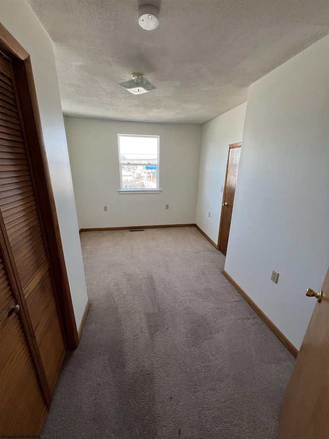 unfurnished bedroom featuring a textured ceiling, baseboards, and carpet flooring