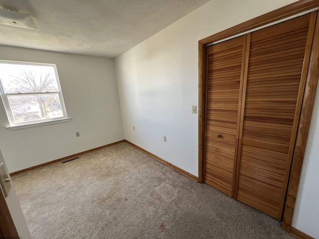 unfurnished bedroom featuring baseboards, a closet, visible vents, and carpet flooring