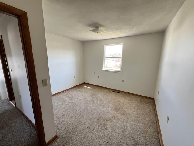 carpeted spare room featuring visible vents and baseboards