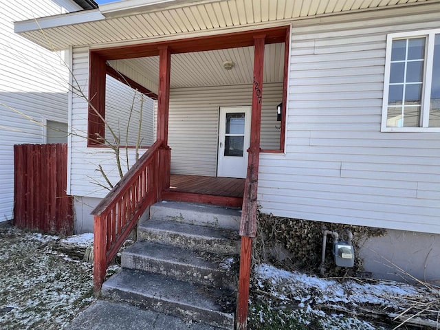 snow covered property entrance with a porch