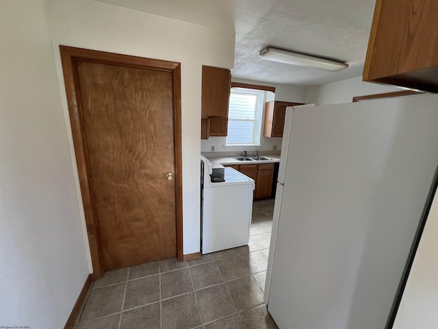 kitchen featuring dark tile patterned floors, light countertops, brown cabinets, range, and freestanding refrigerator