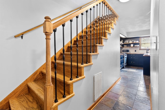 staircase featuring baseboards, visible vents, indoor bar, and stone tile flooring