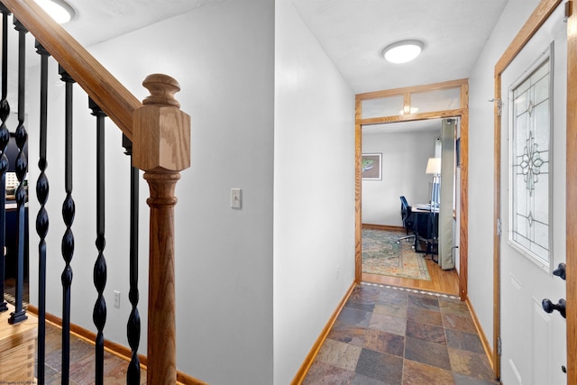 hallway with stone finish flooring, stairway, and baseboards