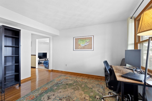 home office featuring wood finished floors, built in features, and baseboards