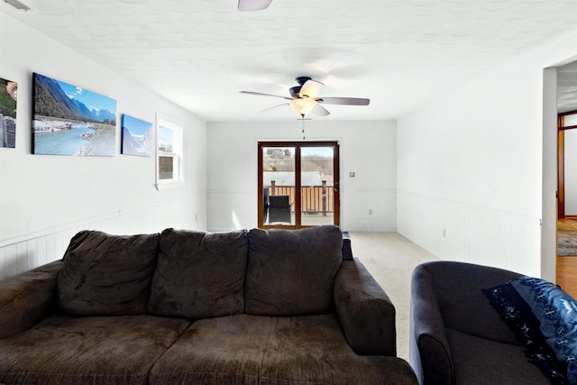 living area featuring carpet floors, a wainscoted wall, ceiling fan, and a textured ceiling