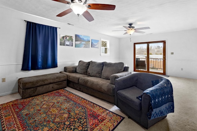 living area featuring carpet floors, visible vents, and a ceiling fan