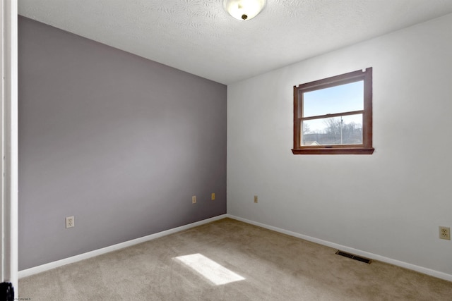 empty room with carpet floors, baseboards, visible vents, and a textured ceiling