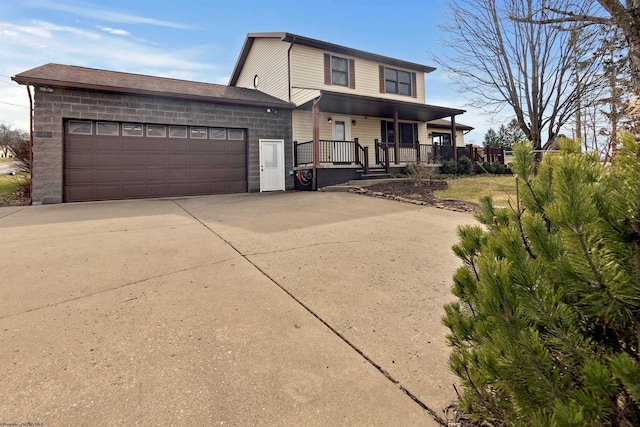 traditional-style house with covered porch, driveway, stone siding, and an attached garage