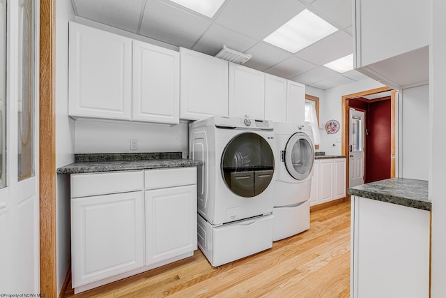 clothes washing area with light wood-style floors, cabinet space, and independent washer and dryer