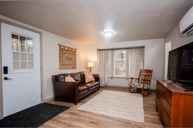 living area with baseboards, wood finished floors, and a wall mounted air conditioner