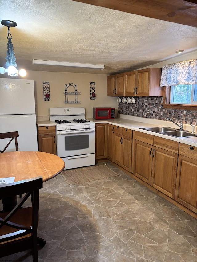 kitchen featuring light countertops, white appliances, a sink, and brown cabinets