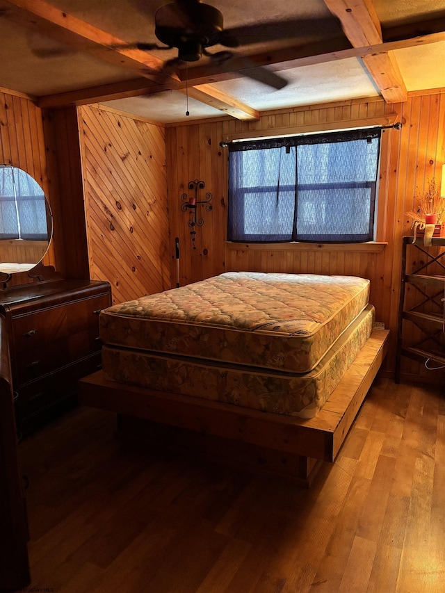 bedroom with light wood-style floors, beam ceiling, ceiling fan, and wooden walls