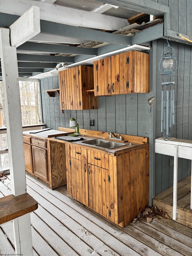 kitchen with brown cabinetry, a sink, wooden walls, and open shelves