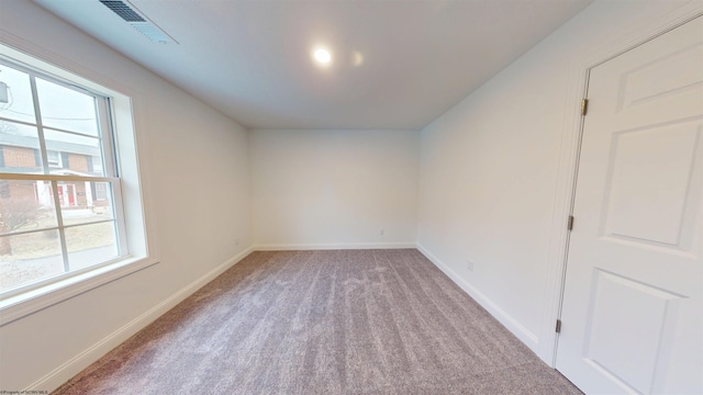 unfurnished room with baseboards, visible vents, and light colored carpet