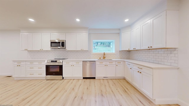 kitchen featuring white cabinets, light wood-style floors, stainless steel appliances, and a sink