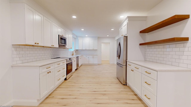 kitchen with white cabinets, light wood-style flooring, appliances with stainless steel finishes, light countertops, and open shelves