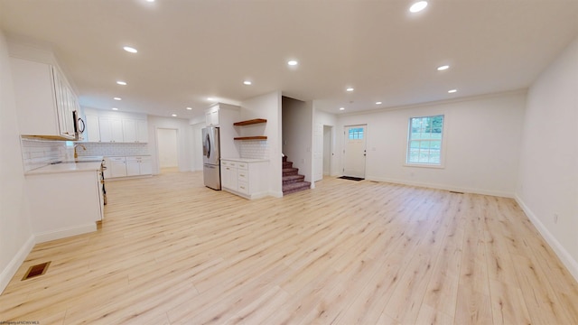 unfurnished living room featuring light wood finished floors, visible vents, a sink, and recessed lighting