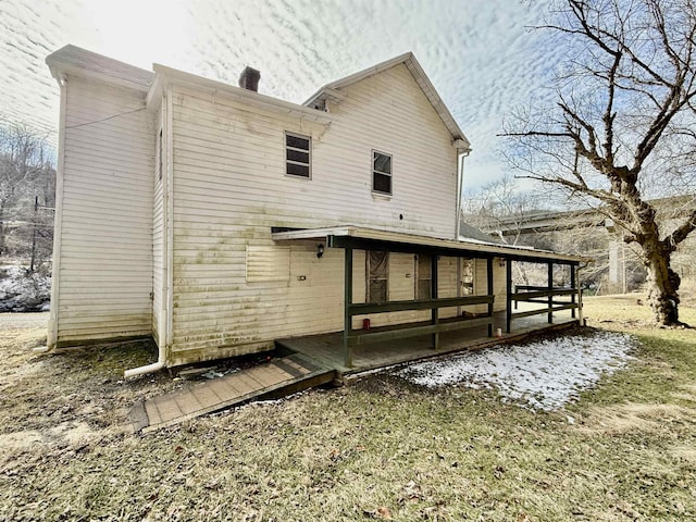 rear view of house featuring a chimney and a wooden deck