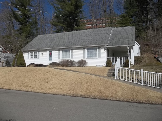 ranch-style house with a porch, roof with shingles, and fence